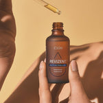 Femme appliquant l’huile REVIZENT™  avec flacon en main